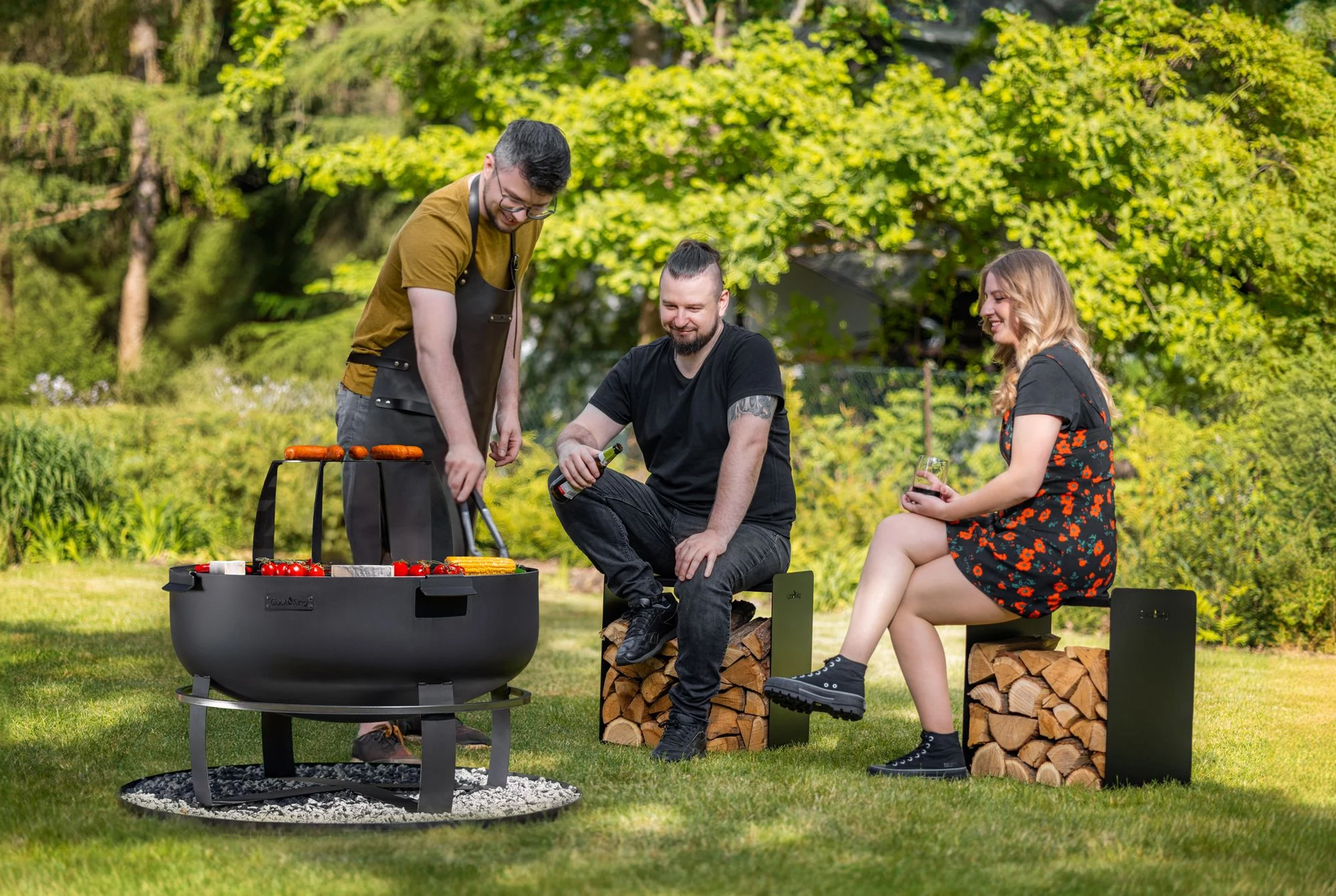 Friends grilling together around a COOK KING fire bowl in the garden