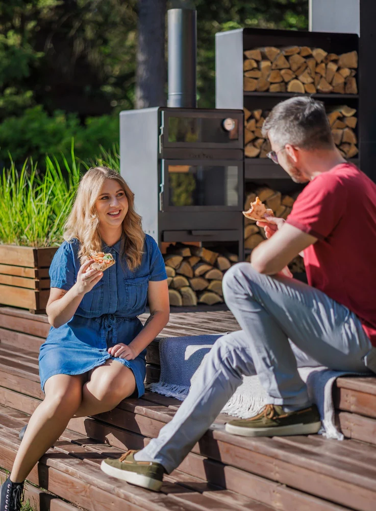 Couple eating pizza next to a COOK KING garden stove